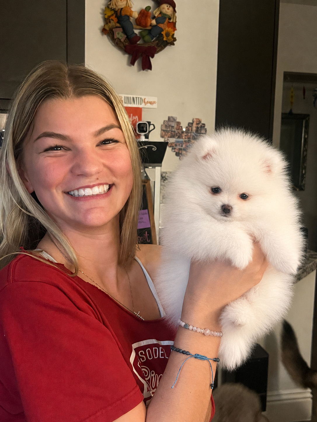 Happy young woman holding her new white Pomeranian puppy from Cream-Puffs