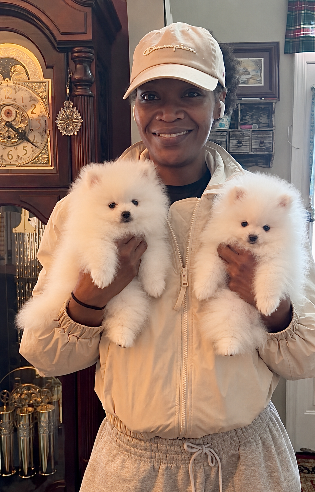 Woman holding two white Pomeranian puppies from Cream-Puffs Pomeranians