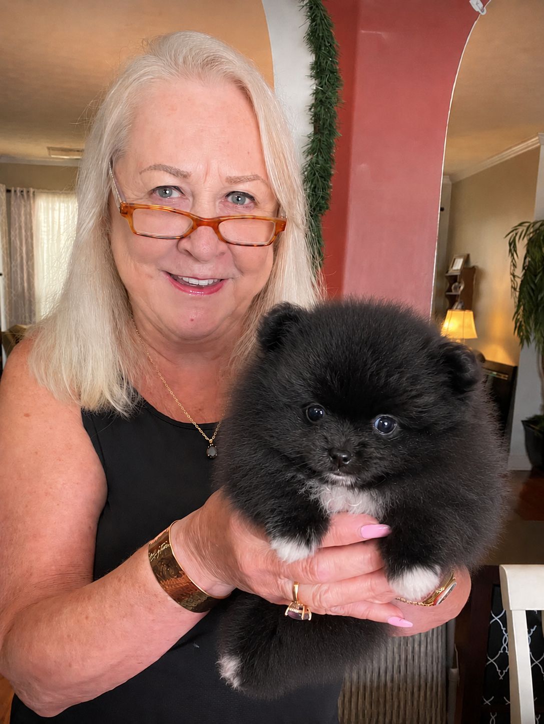 Woman with glasses holding her new black Pomeranian puppy from Cream-Puffs Pomeranians