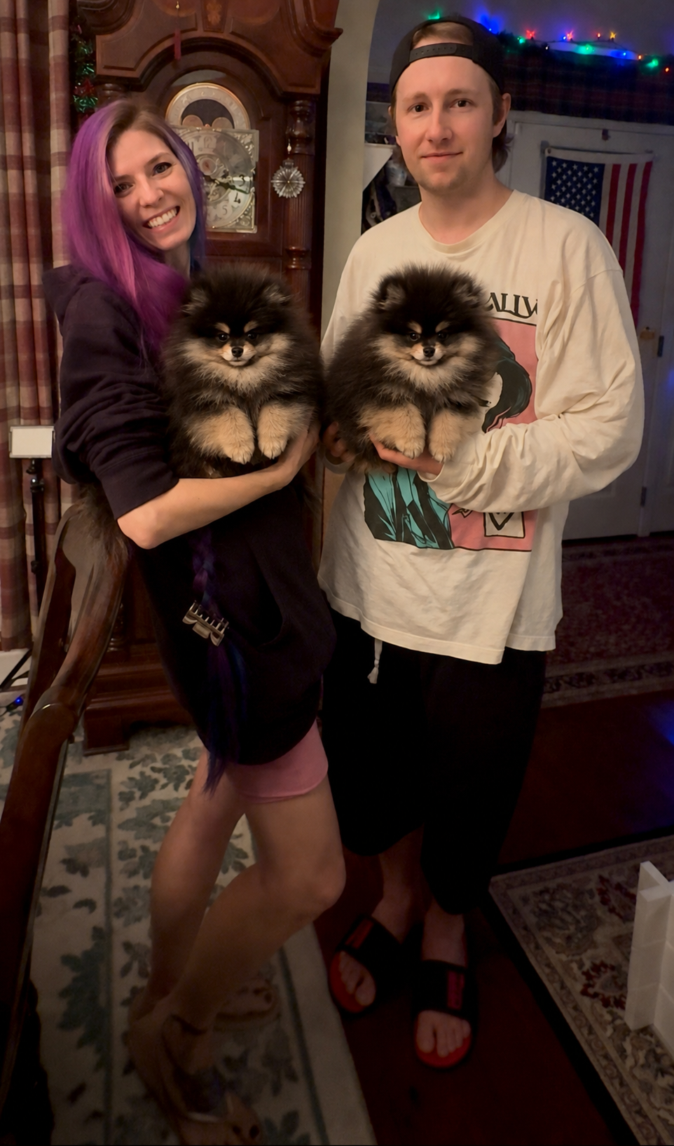 Couple each holding a black and tan Pomeranian puppy from Cream-Puffs Pomeranians