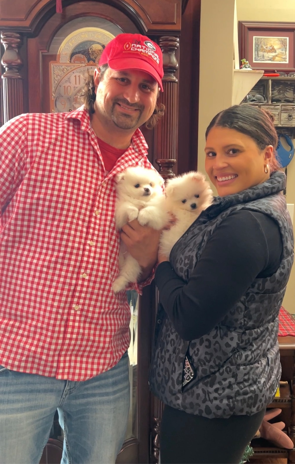 Couple holding two fluffy white Pomeranian puppies indoors from Cream-Puffs