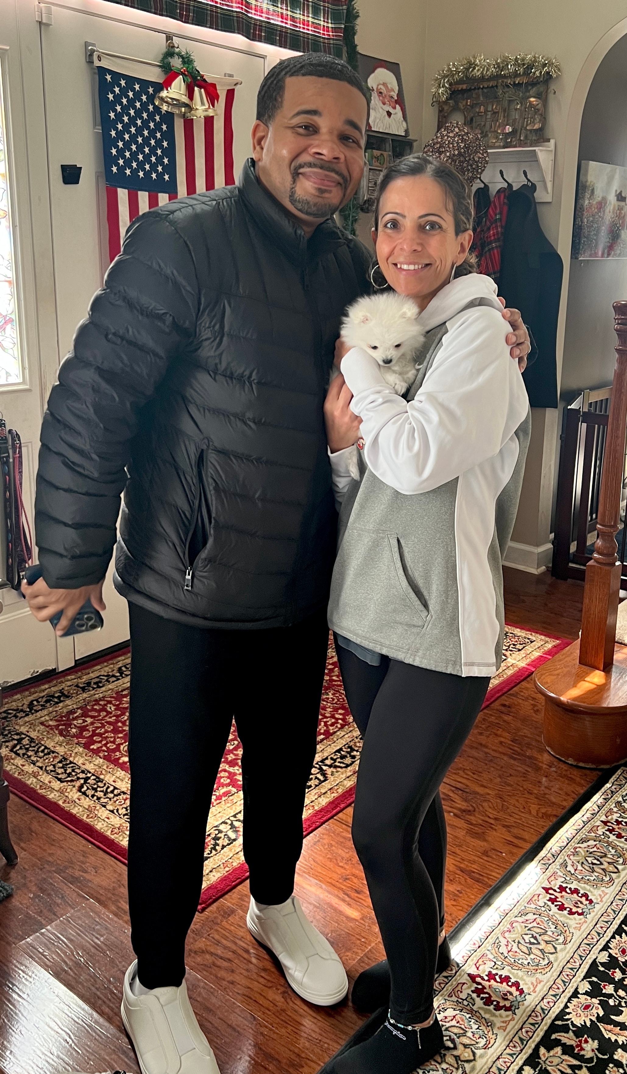 Couple smiling indoors with their new white Pomeranian puppy from Cream-Puffs